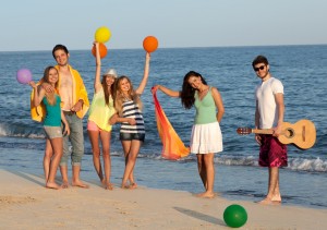 Group of young people enjoying beach party with guitar and balloons